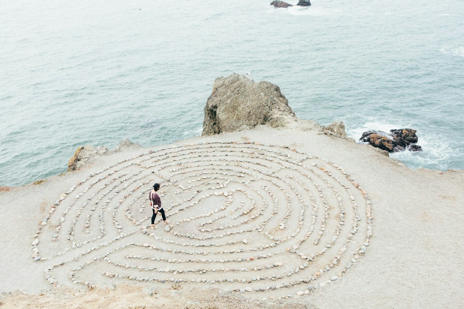 Spirituelle Beratung am Meer: Einzelperson in Steinkreis nahe Klippe– Sinnbild für innere Einkehr, Übergangsphasen und seelische Ausrichtung